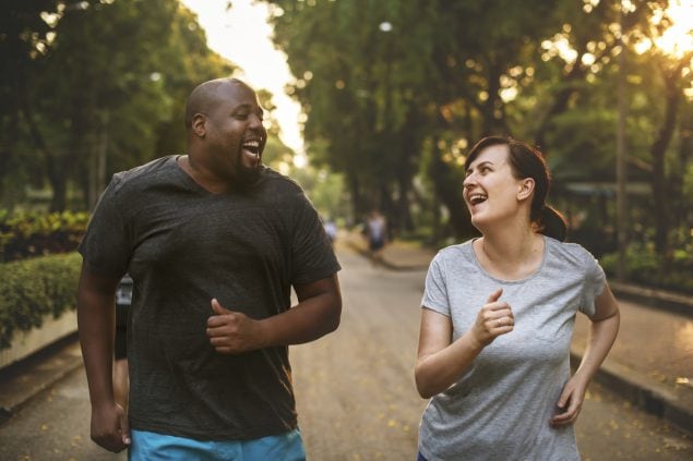 Couple jogging together and laughing in the park.