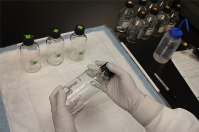 Una persona en un laboratorio sostiene una botella de vidrio