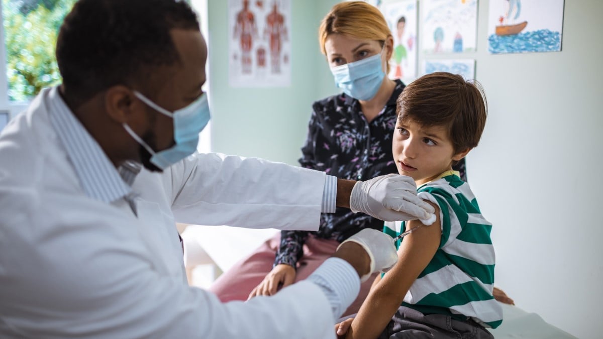 Photo of a doctor giving an HPV vaccine to a boy while his mother looks on
