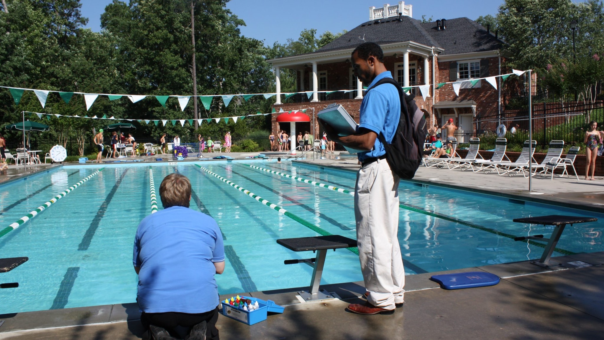 Photo of an inspector holding a clipboard and standing next to a public pool.