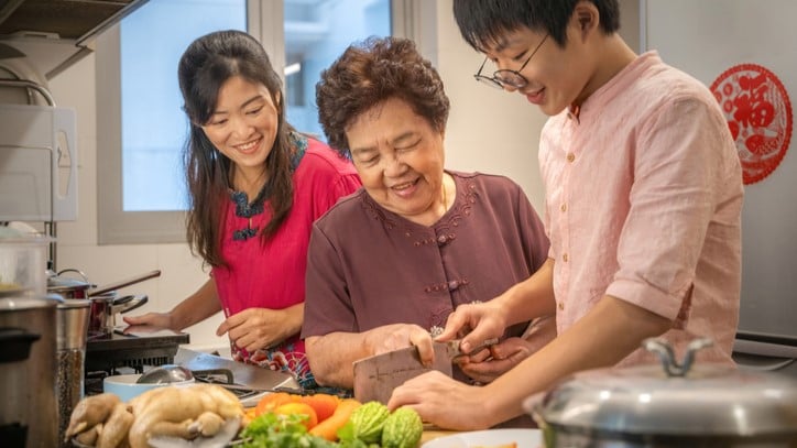 Photograph of a son, mother, grandmother preparing bittermelon and chicken.