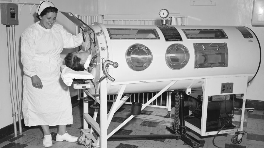 Historic 1960 photo of nurse caring for polio patient in an iron lung.
