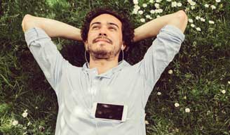 Man laying in the grass listening to mobile device
