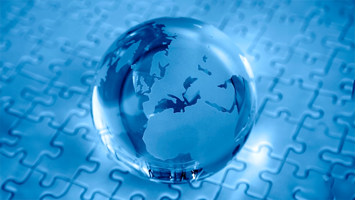 Transparent globe on top of blue puzzle.