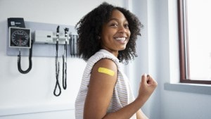 Black teenage girl making a muscle with her arm that also has a Band-Aid on it