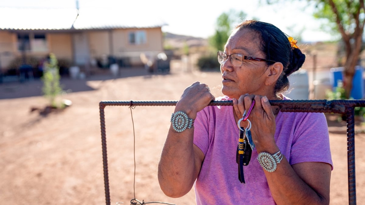 Mujer navajo de pie delante de la entrada de su casa en Monument Valley, Arizona