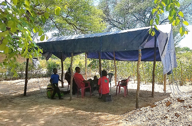 group sitting beneath a shelter