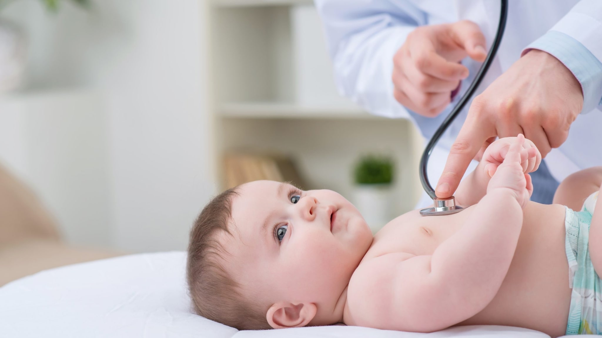 A doctor uses a stethoscope to listen to a baby's lungs.