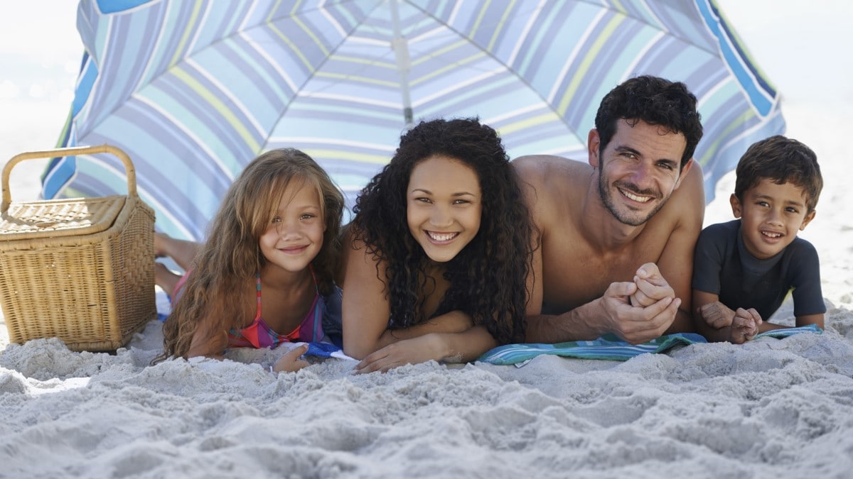 Photo of a family under a large umbrella on the beach