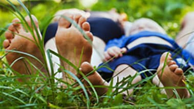 Bare feet of a man and child in grass.