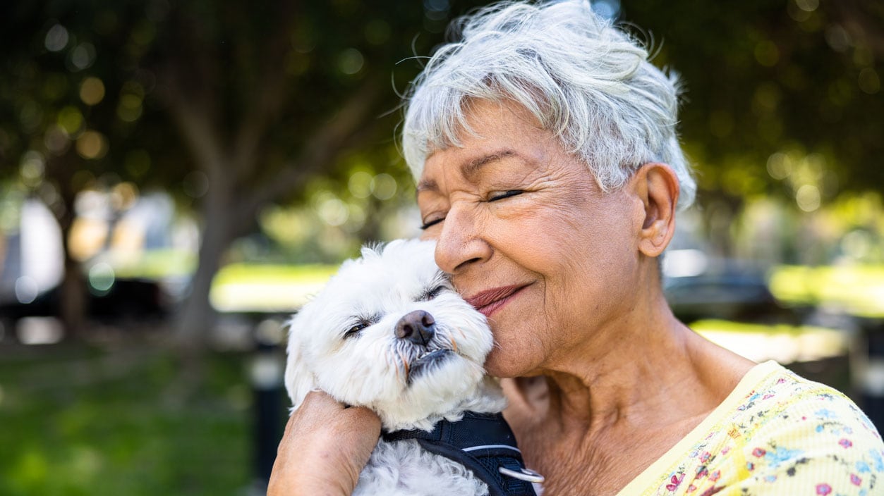 Senior woman holding her puppy outdoors.
