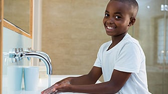 A young boy washes his hands with soap and water