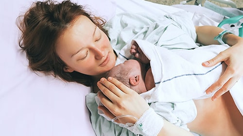A mother receiving antibiotics while holding her newborn