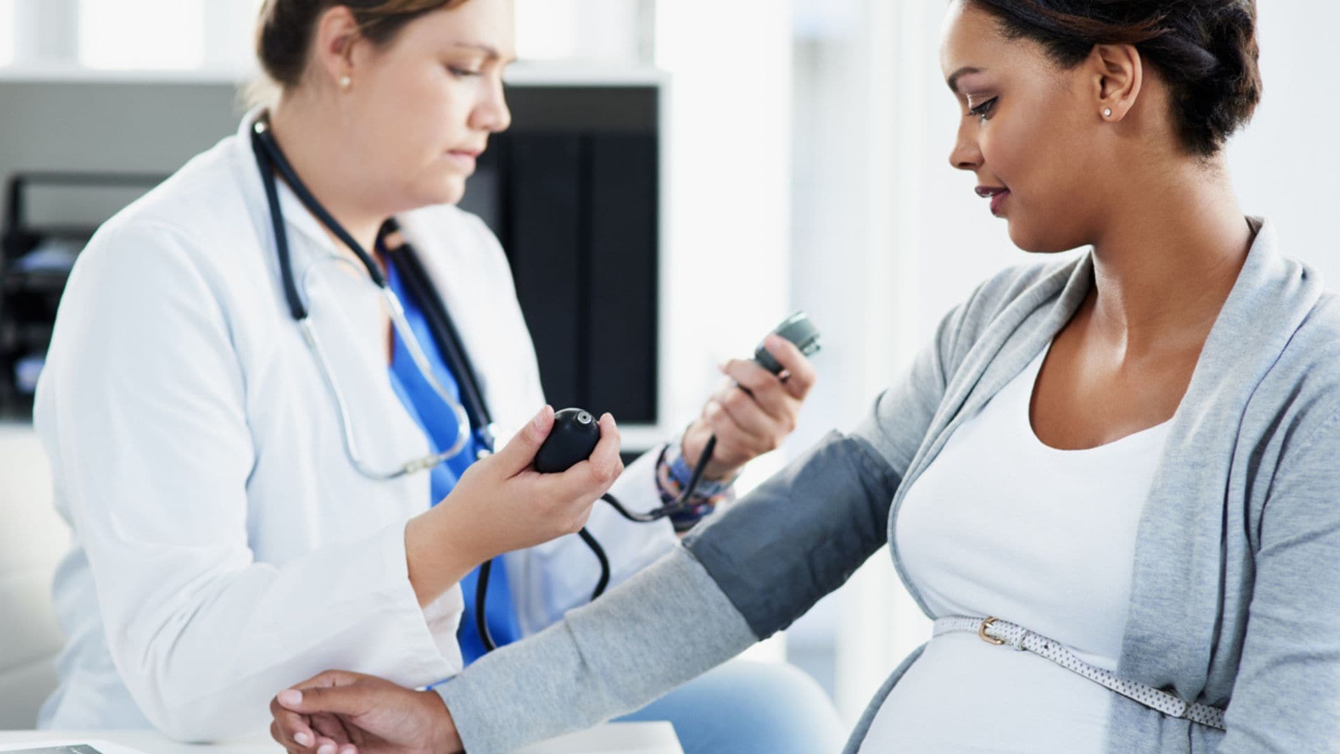 Doctor taking pregnant woman's blood pressure