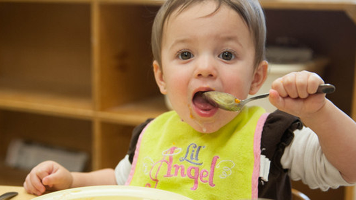 18 month old child eating with spoon