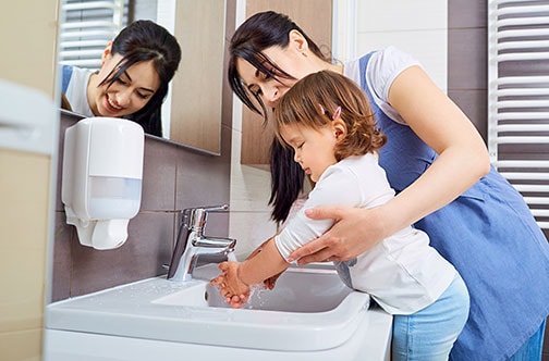 Madre ayudando a su hija a lavarse las manos.