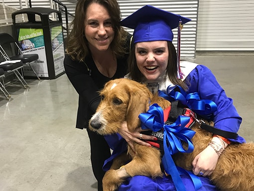 Sarah in graduation outfit with Mom and dog, Oliver