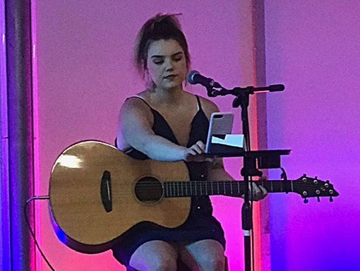 Sarah performs on stage with guitar