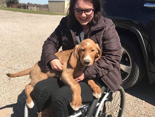 Sarah in a wheelchair with a puppy in her lap