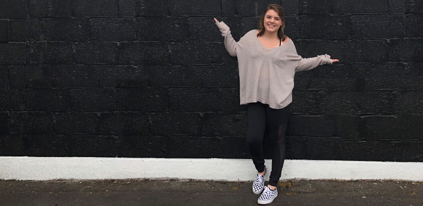Sarah standing in front of a black concrete block wall