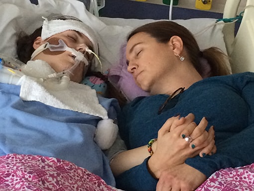 Sarah and mom laying next to each other holding hands