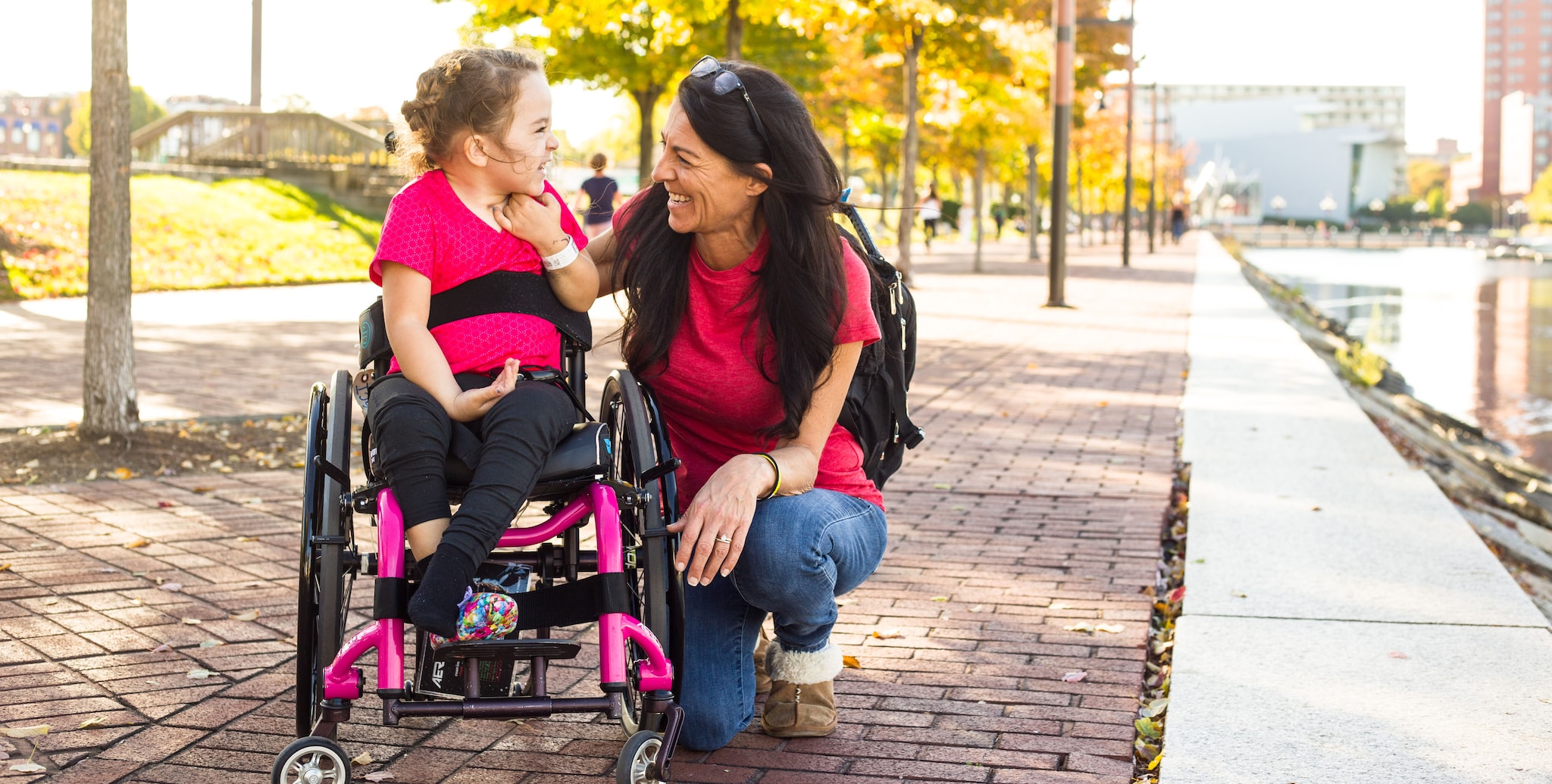 young girl with AFM in wheelchair laughing with her mom