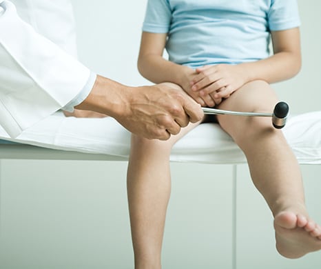 doctor testing a young boy's reflexes