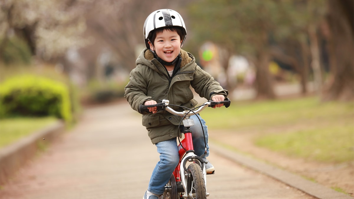 The boy is riding his bike happily.
