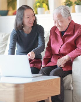 Younger woman showing elderly woman how to use a laptop computer