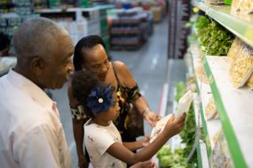 Grandparents and granddaughter choosing healthy produce at the grocery store.