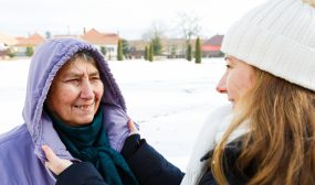 Younger woman helping older woman adjust winter coat
