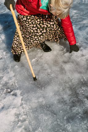 Older woman walking on icy street in winter.