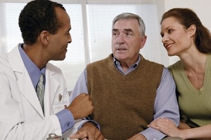 Doctor speaking with aged fellow and younger woman