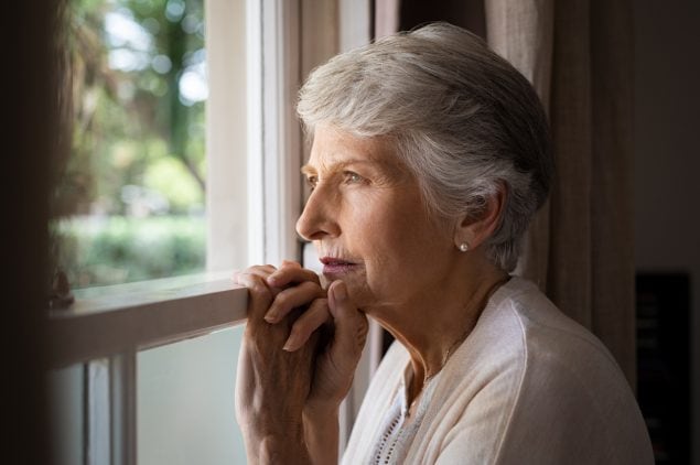 An older woman gazes out the window