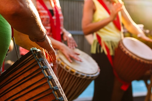 Close-up of people's hands playing on djembe drums.
