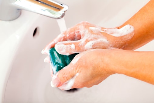 A person washing hands with green soap.