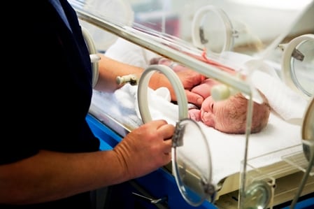 image of a premature infant being cared for by a healthcare assistant