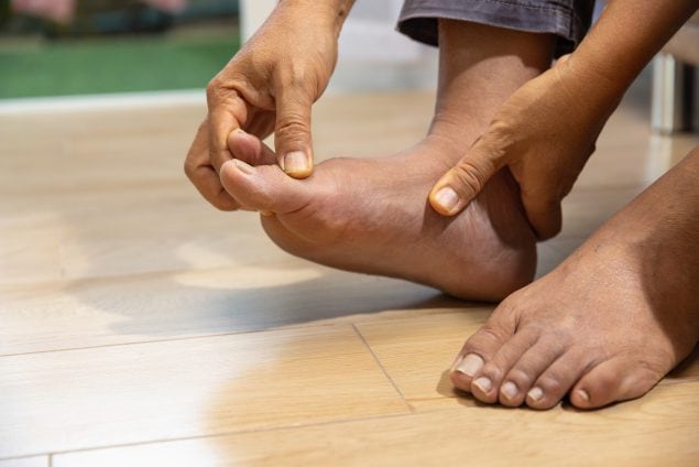A close-up of a person massaging their foot with painful swollen gout inflammation.
