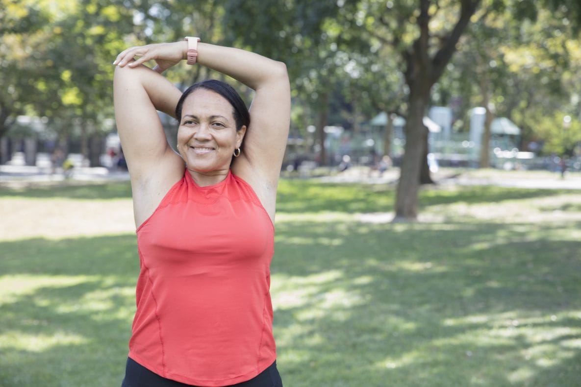 Woman in a park stretching in preparation for exercise.