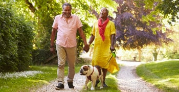 older black couple walking dog in the park