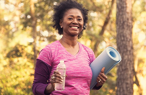 Woman heading to exercise, carrying a yoga mat