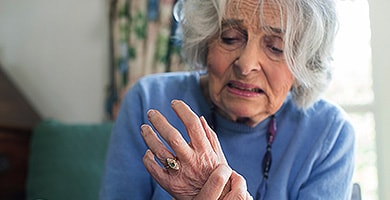 Older woman holding her arthritic hand