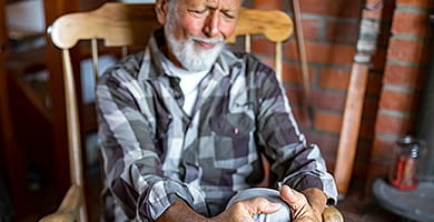 رجل كبير السن يمسك بالركبة المصابة بالتهاب المفاصل