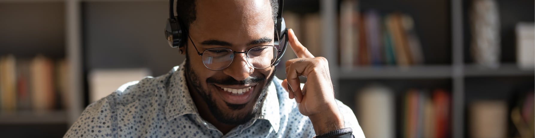 Smiling man wearing headphones and talking into the speaker.