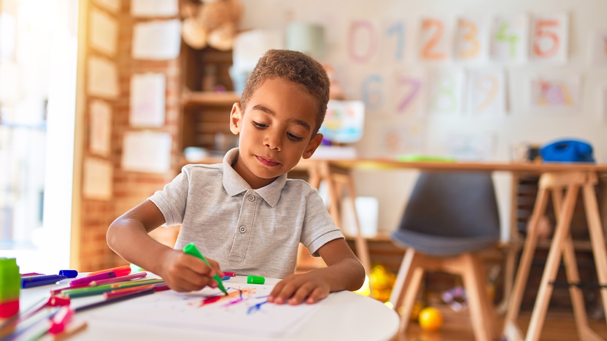 child writing and coloring in a classroom