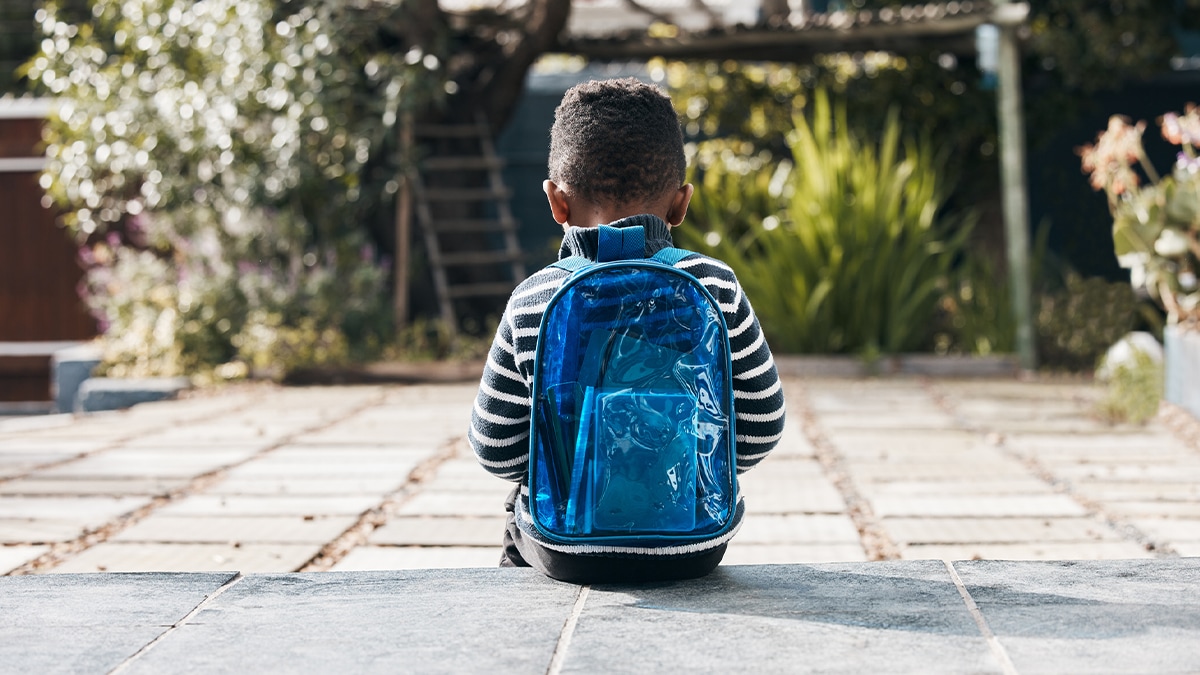 Boy sitting on ground with a backpack