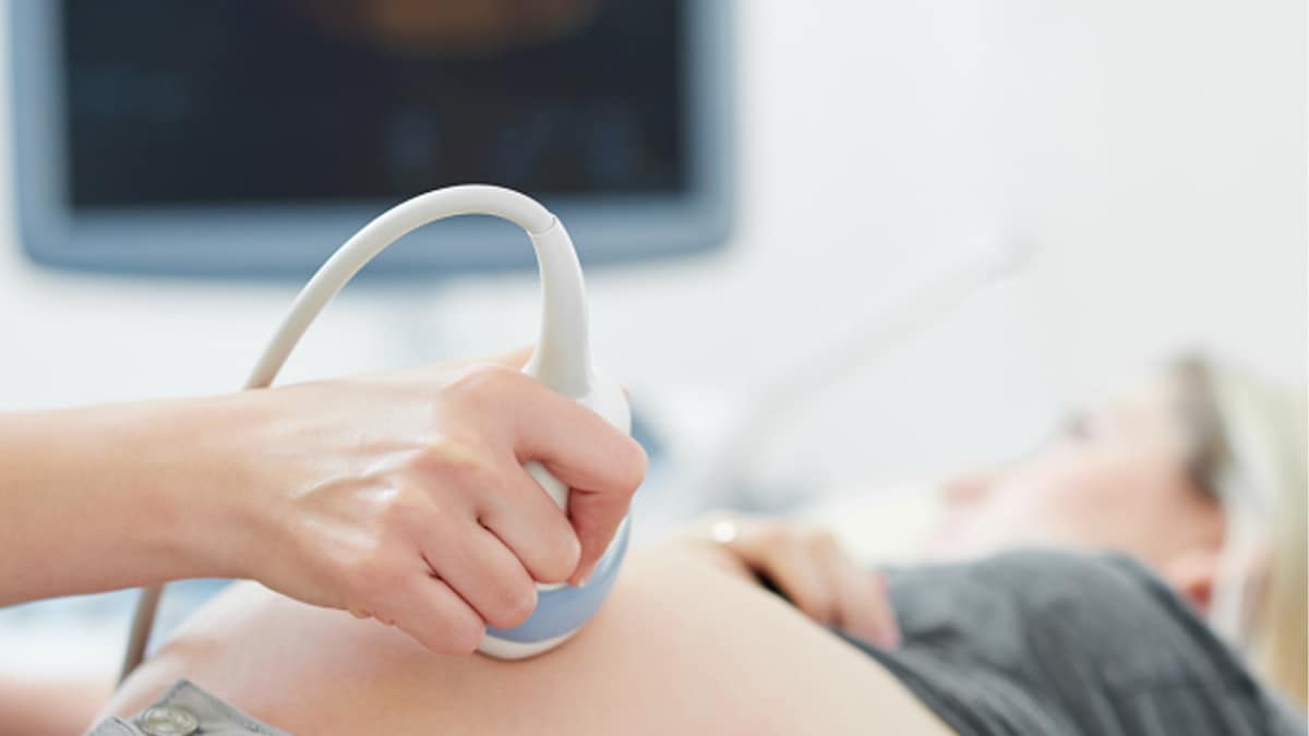 Doctor using ultrasound machine on pregnant person