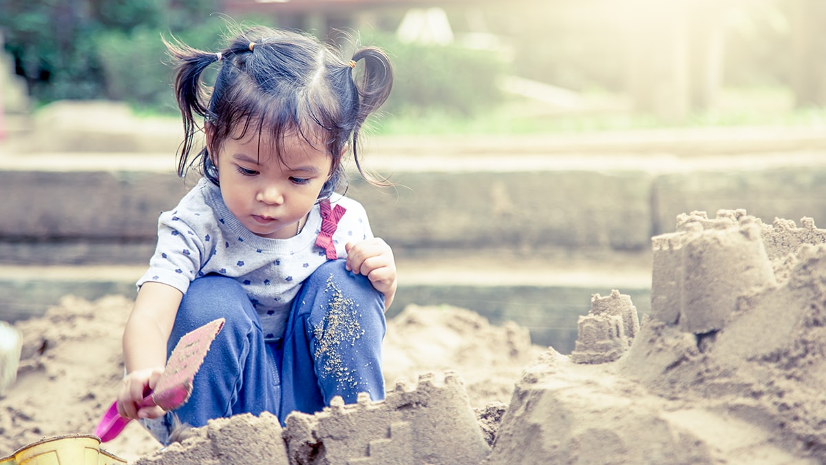 Young girl playing in a sandbox.