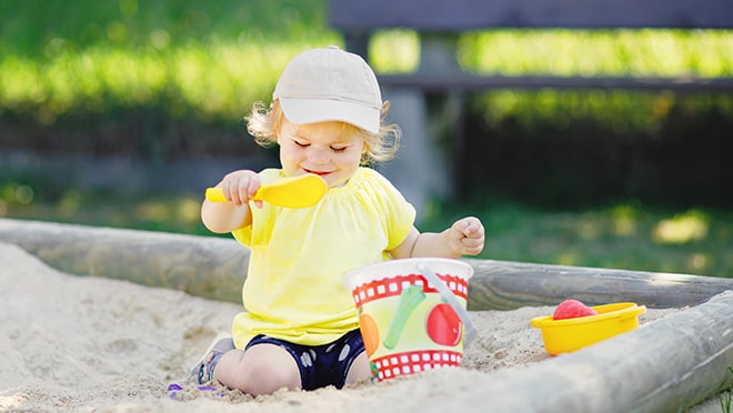 Child playing in sandbox with bucket and shovel,