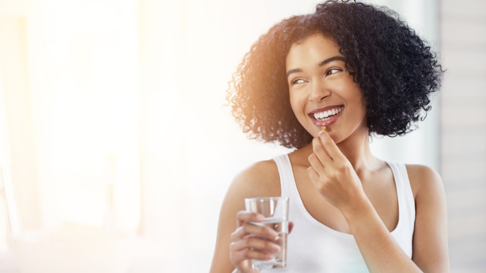 Young woman smiles taking a vitamin.